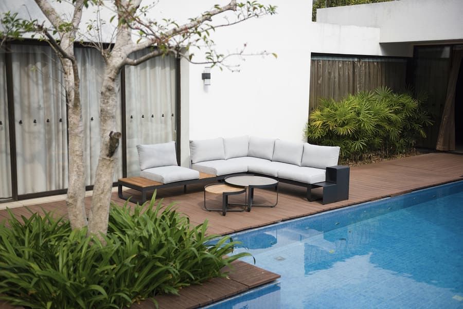 Terrasse extérieure avec canapé d'angle, tables basses et piscine.