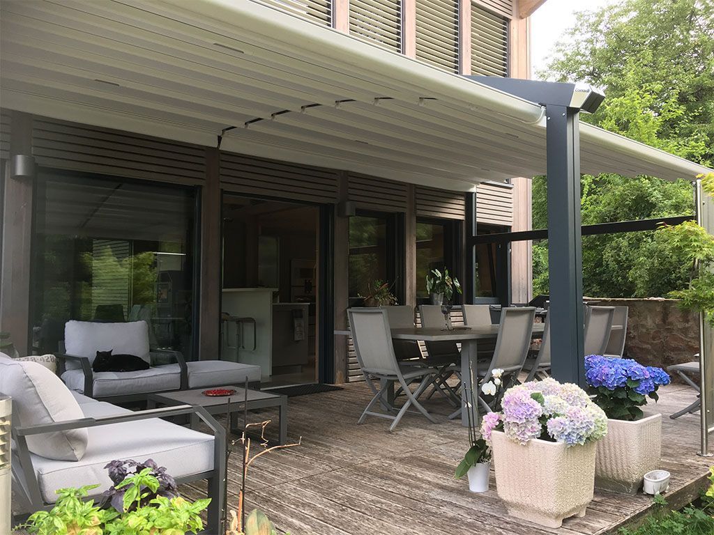 Patio avec pergola moderne, mobilier de jardin et hortensias en pot.
