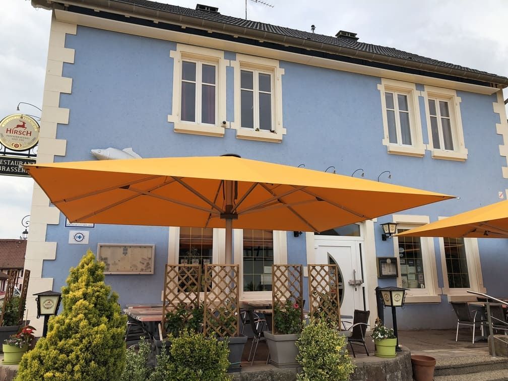 Restaurant avec façade bleue et parasols jaunes pour les places assises en terrasse.