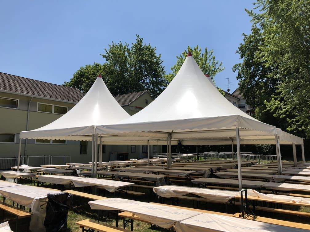Deux tentes blanches au-dessus des tables de pique-nique à l'extérieur.