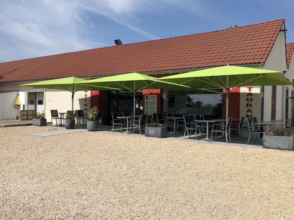Restaurant avec parasols vert citron et terrasse sous un toit de tuiles rouges.