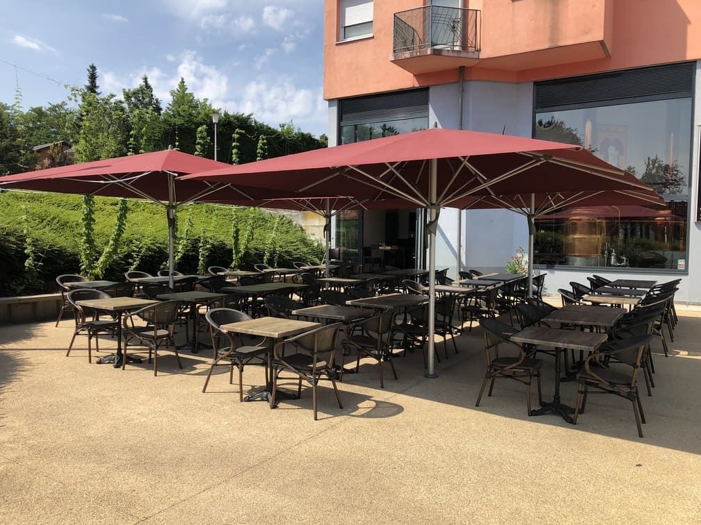 Terrasse de restaurant avec tables et chaises disposées sous des parasols rouges.