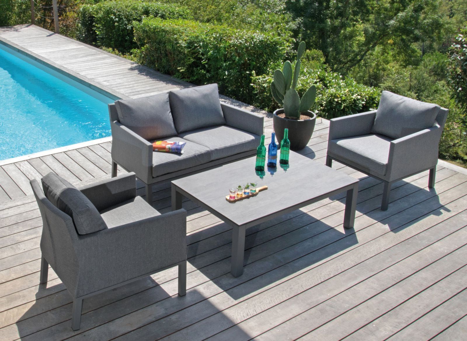 Ensemble de mobilier de jardin gris au bord d'une piscine sur une terrasse en bois.