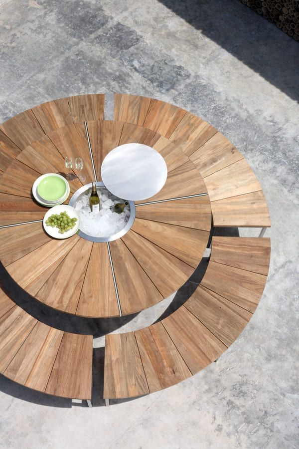 Table ronde d'extérieur en bois avec glacière intégrée, verres et assiettes.