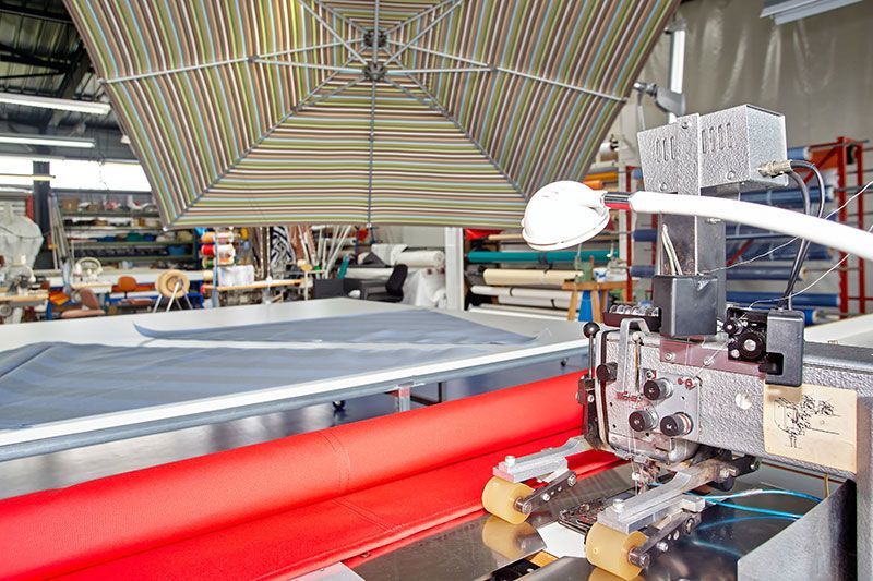 Machine de découpe de tissu automatisée dans un atelier, matériaux rouges et gris, éclairage vif.