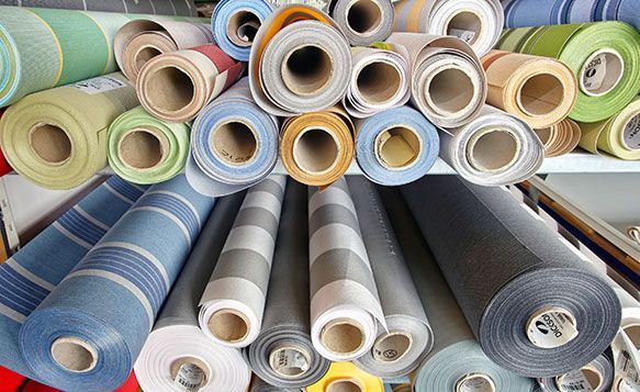 Des rouleaux de tissu de couleurs variées sur des étagères.