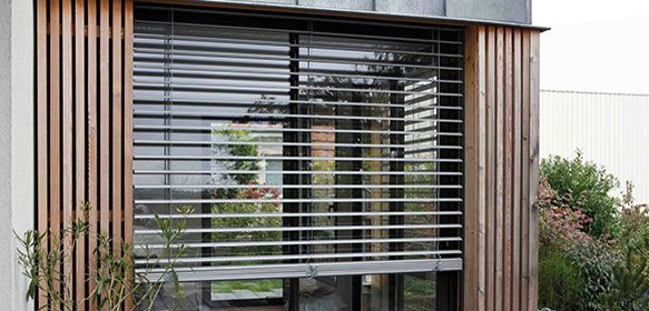 Fenêtre avec stores horizontaux et lamelles verticales en bois.