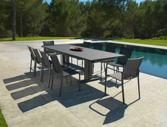 Ensemble repas d'extérieur avec table et chaises gris foncé au bord de la piscine. Cadre ensoleillé.
