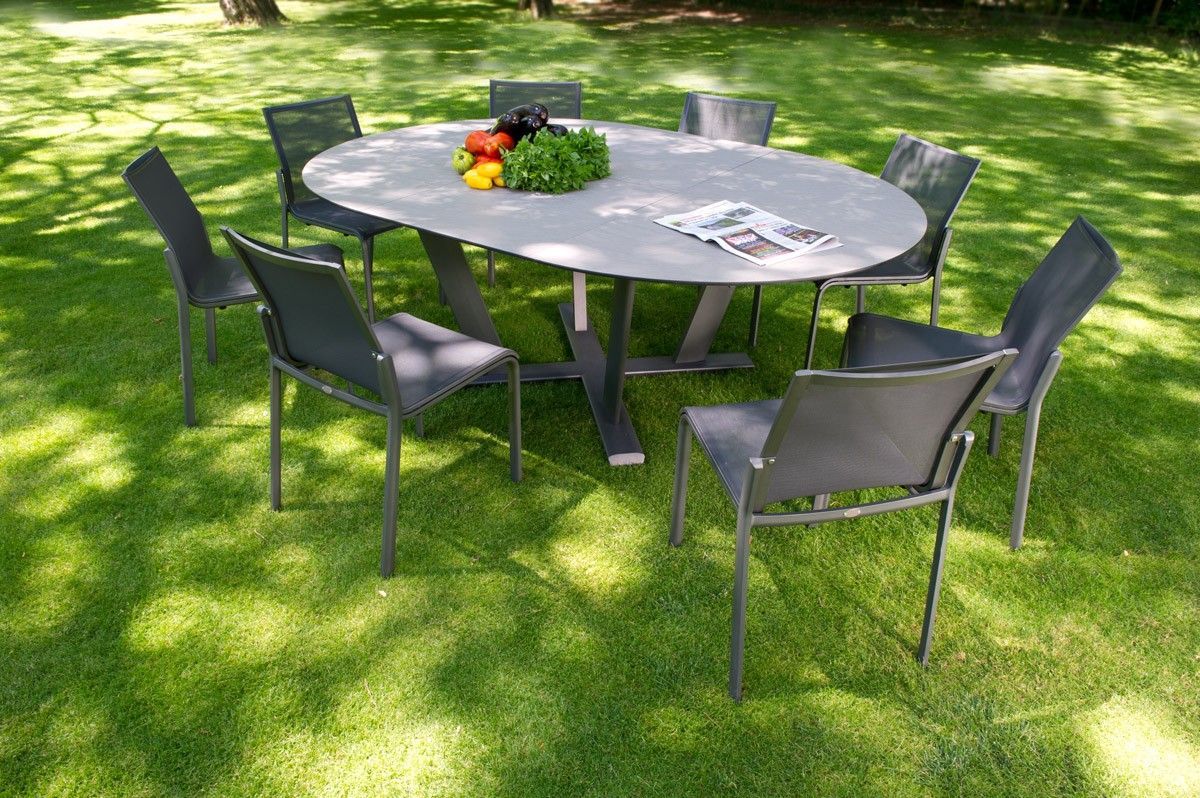Table et chaises de patio ovales installées sur une pelouse verte, avec de la nourriture sur la table.