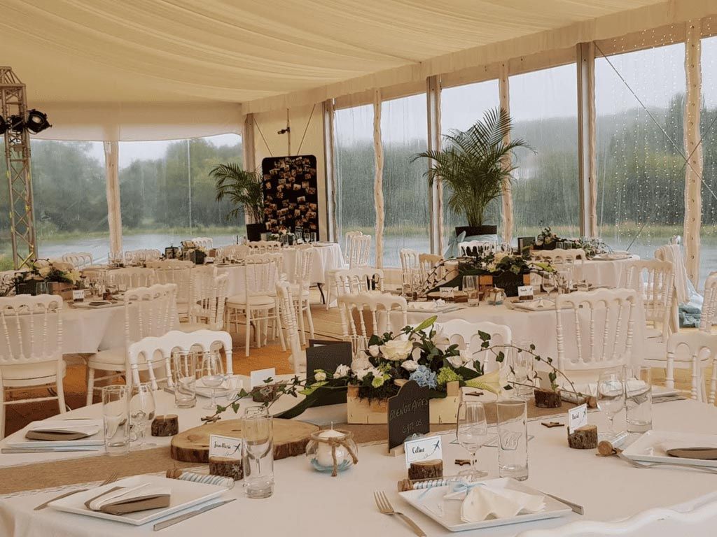 Tente de réception de mariage avec tables dressées pour les invités, donnant sur un lac.