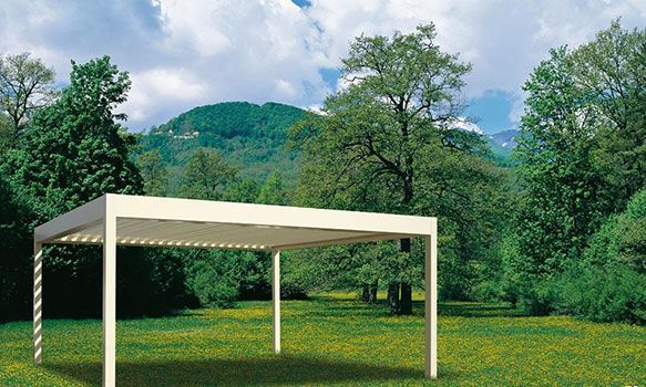 Pergola dans une prairie avec des arbres et des montagnes en arrière-plan.