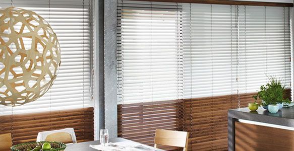 Coin repas avec stores en bois, stores blancs et luminaire décoratif.