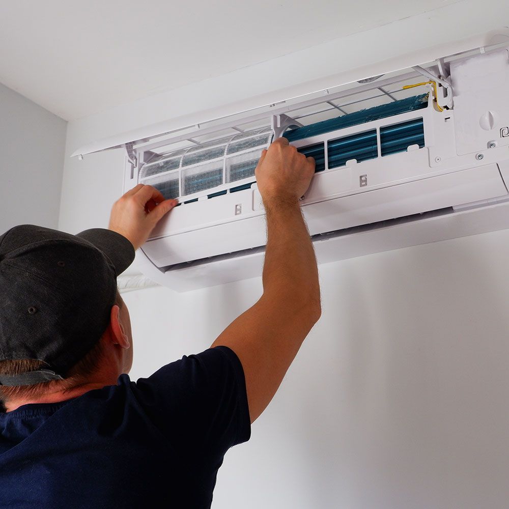Technicien installant une climatisation au-dessus d'une fenêtre dans une maison