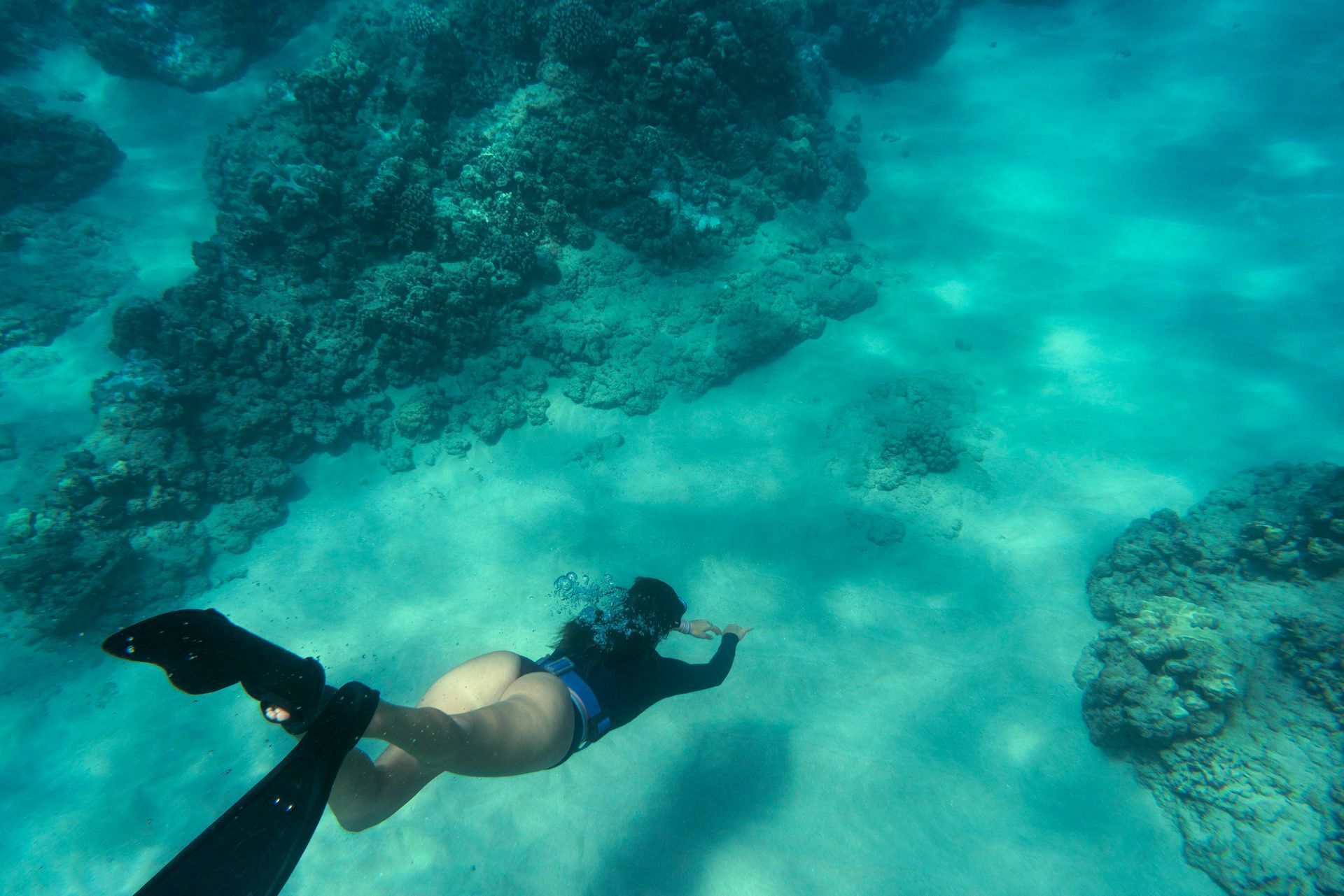 Un plongeur en apnée nage au-dessus d'un récif corallien turquoise avec des poissons