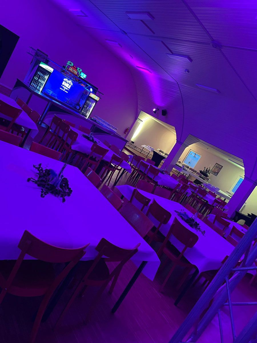 Ein Raum mit violetten Lichtern und Tischen und Stühlen