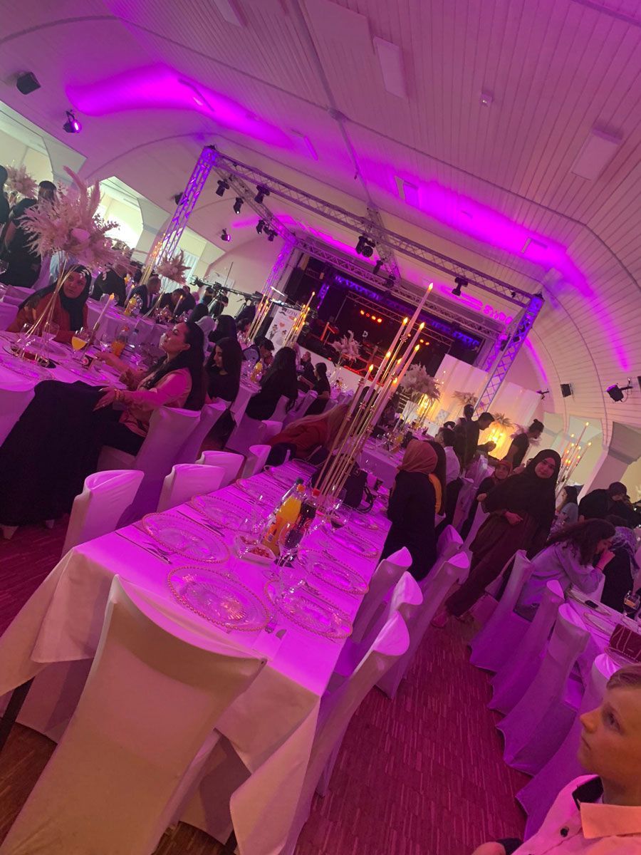 Ein großer Raum voller Tische und Stühle und violetter Lichter.