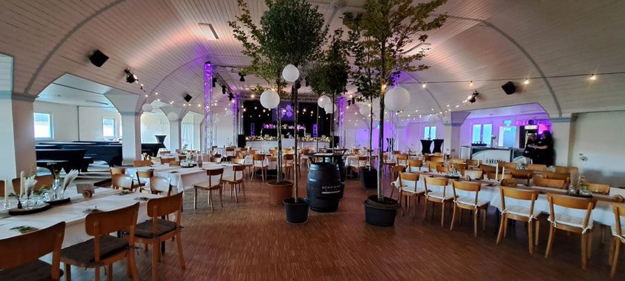 Ein großer Raum mit Tischen und Stühlen und einer Projektionsleinwand.