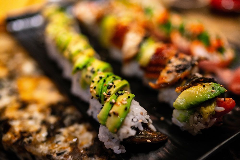 Eine Nahaufnahme einer Sushi-Rolle mit Avocado auf einem Teller.