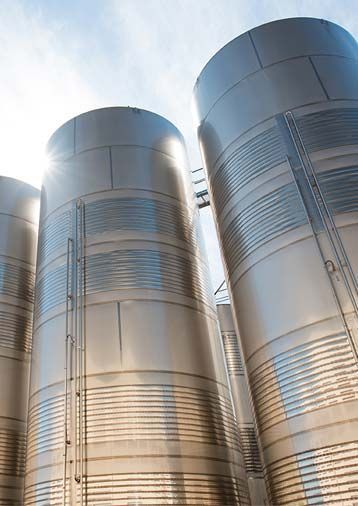 Una fila de silos de acero inoxidable colocados uno al lado del otro en una fábrica.