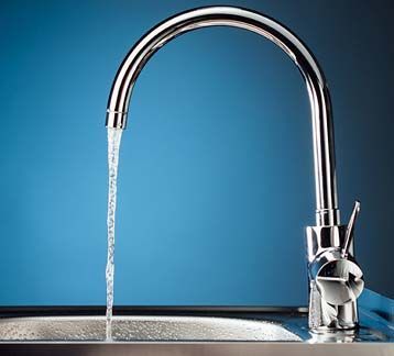 Un grifo deja correr agua en un fregadero con un fondo azul.