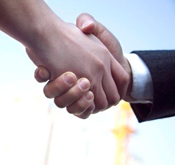Un hombre con traje le da la mano a otro hombre.