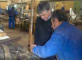 Dos hombres están trabajando en una máquina en una fábrica.