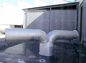 Una gran tubería de acero inoxidable se encuentra frente a un edificio.