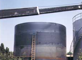 Una grúa está levantando un gran tanque de metal en una fábrica.