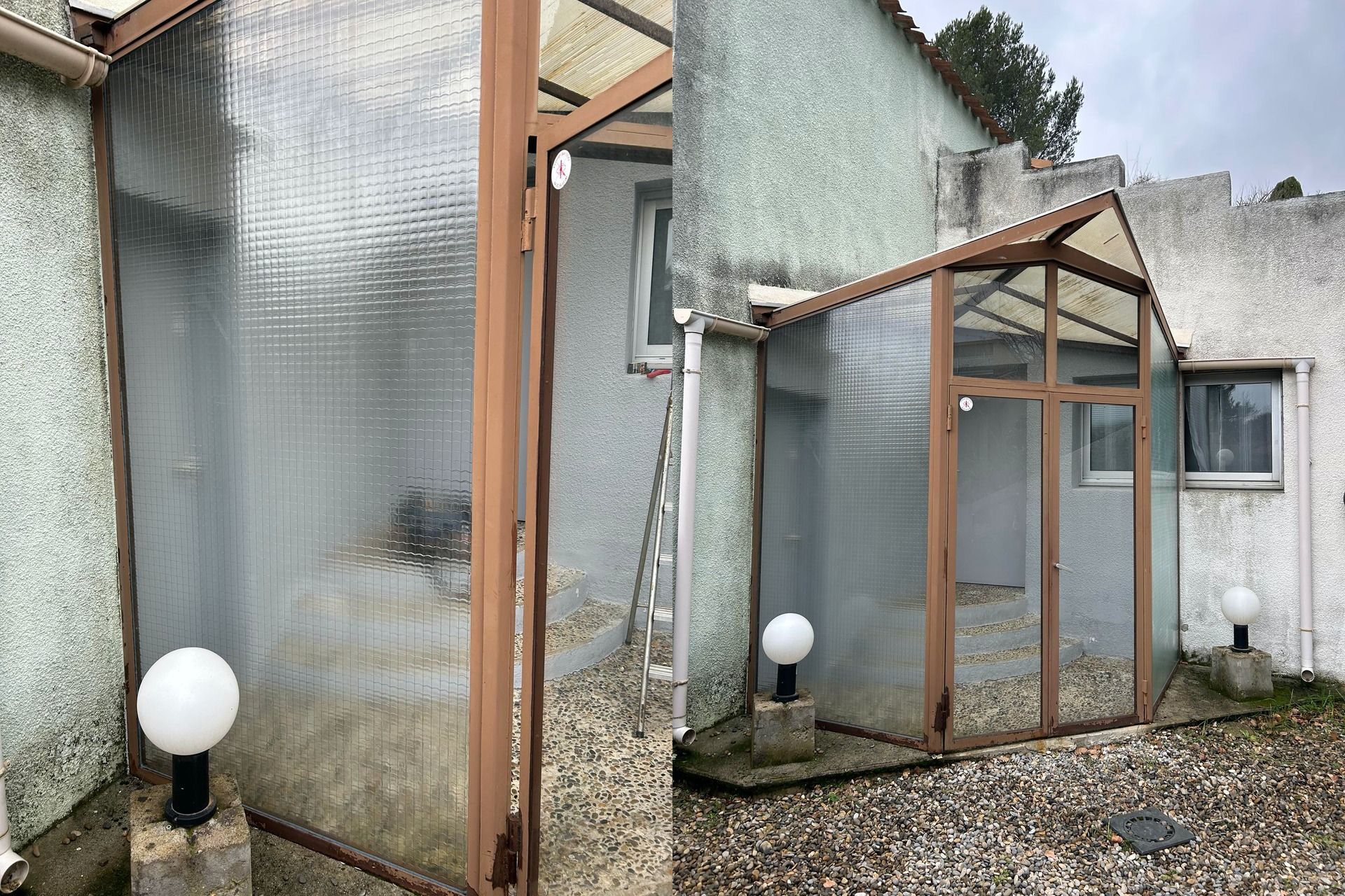 Serre à cadre brun attachée à un bâtiment en stuc; panneaux en plastique ondulé transparent; deux lumières sphériques.