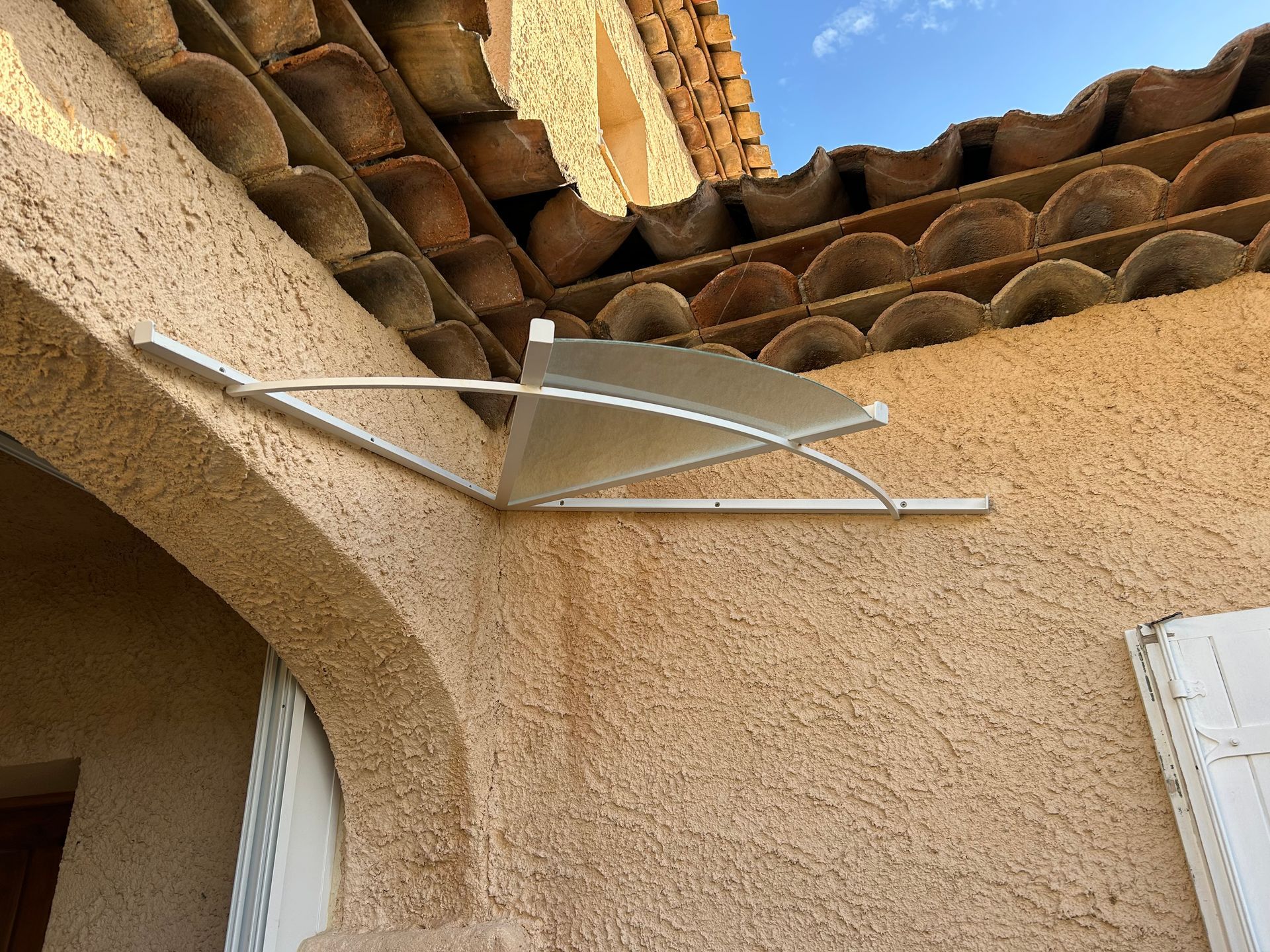 Petit auvent métallique incliné au-dessus d'une porte.