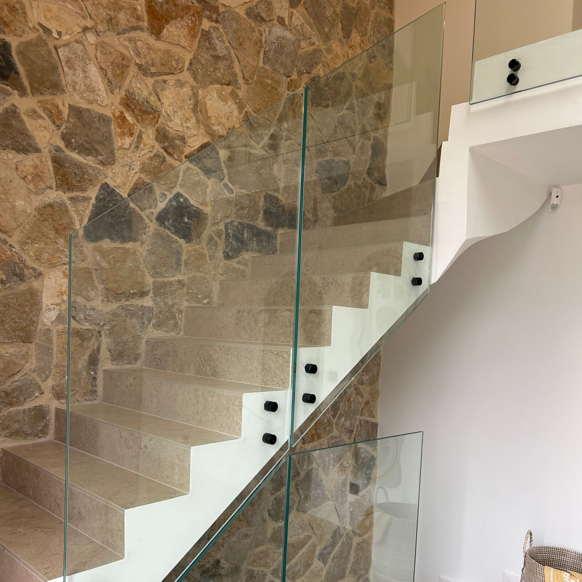 Escalier en pierre avec garde-corps en verre. Escalier blanc contre un mur en pierre.