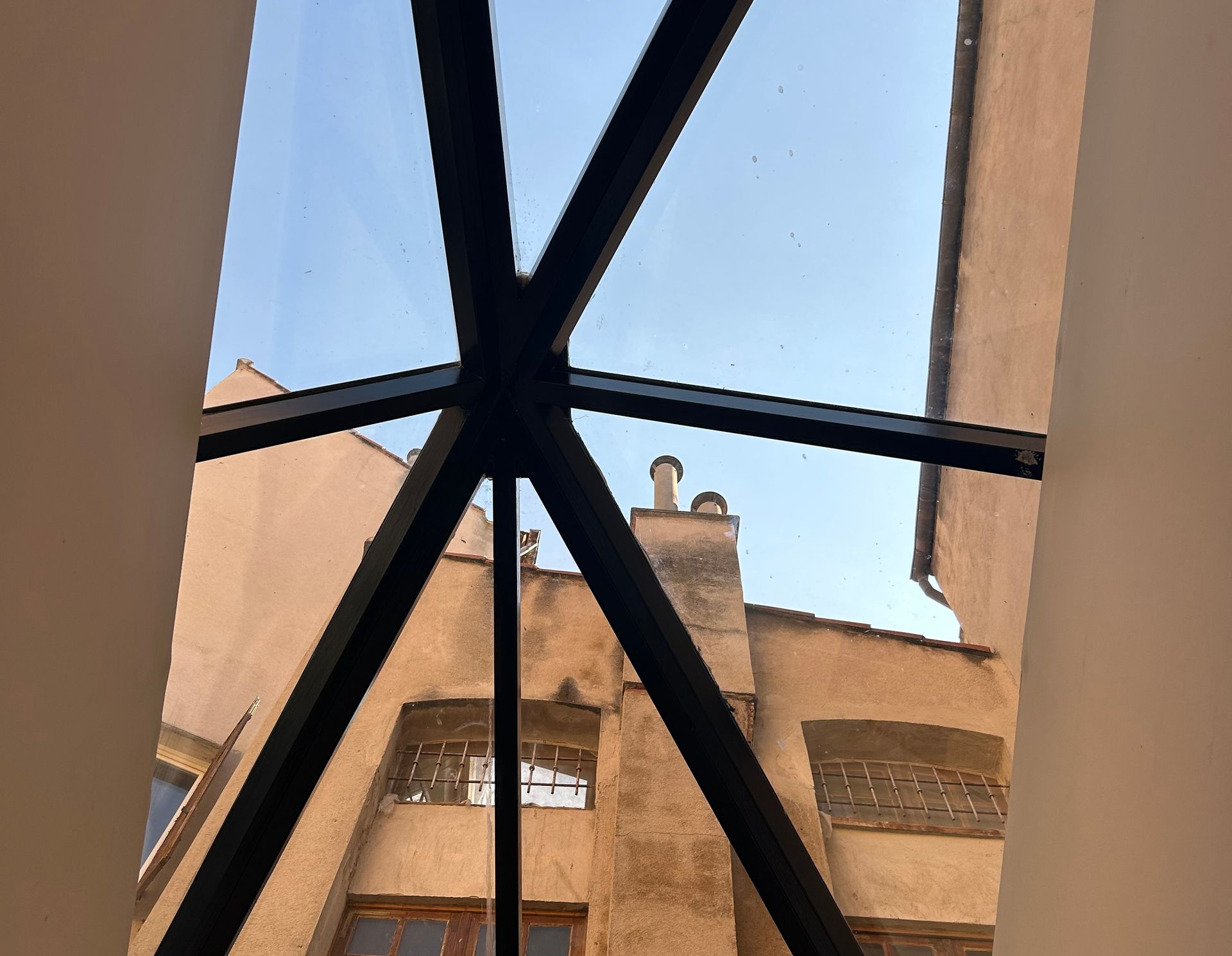 Regardant à travers une lucarne vers un vieux bâtiment et un ciel bleu clair.