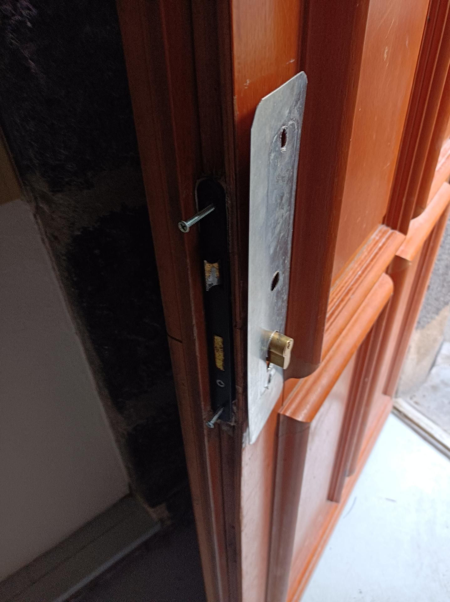 Gros plan sur une porte en bois avec une plaque de verrouillage argentée et une serrure en laiton sur le cadre.