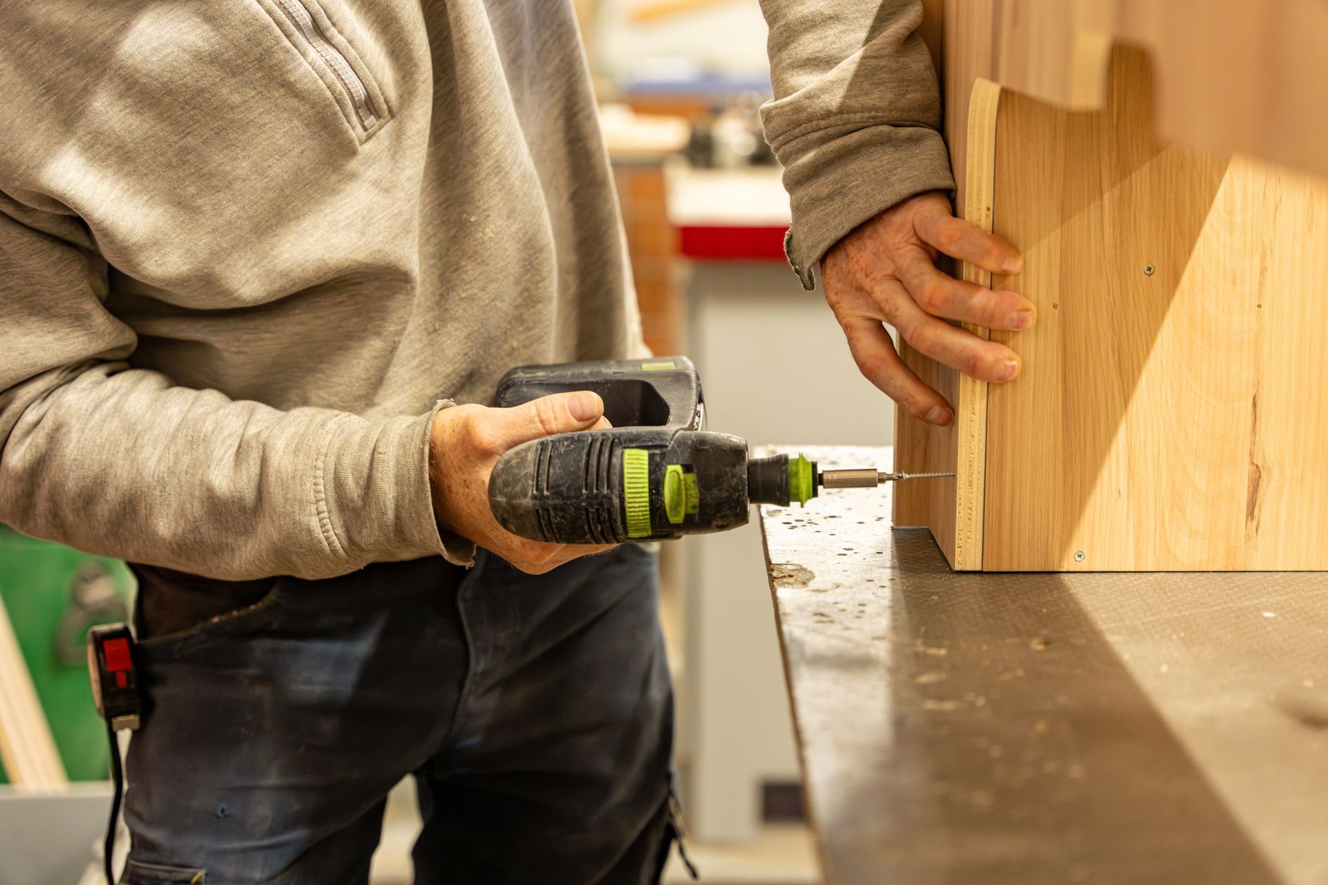 Une personne fait un trou dans une planche sur un établi dans un atelier.