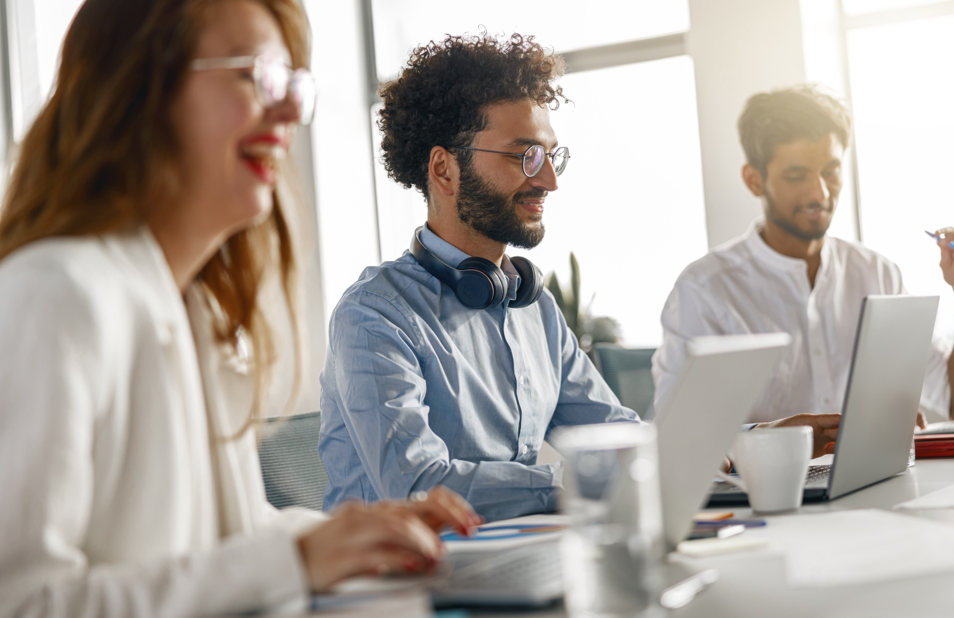 Un grupo de personas están sentadas en una mesa con computadoras portátiles.