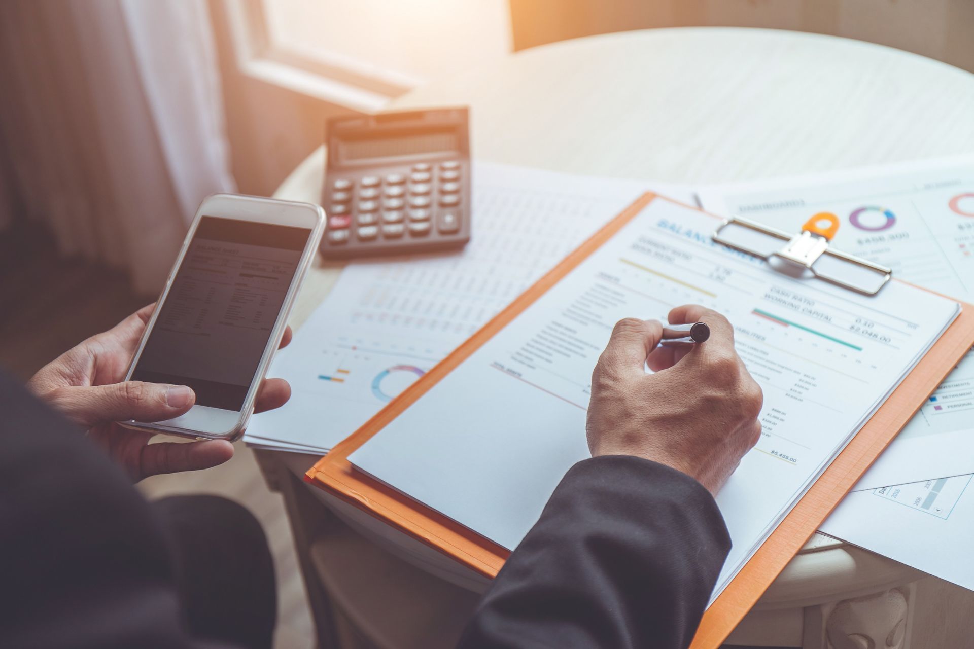 Un hombre sostiene un teléfono celular y escribe en un portapapeles.