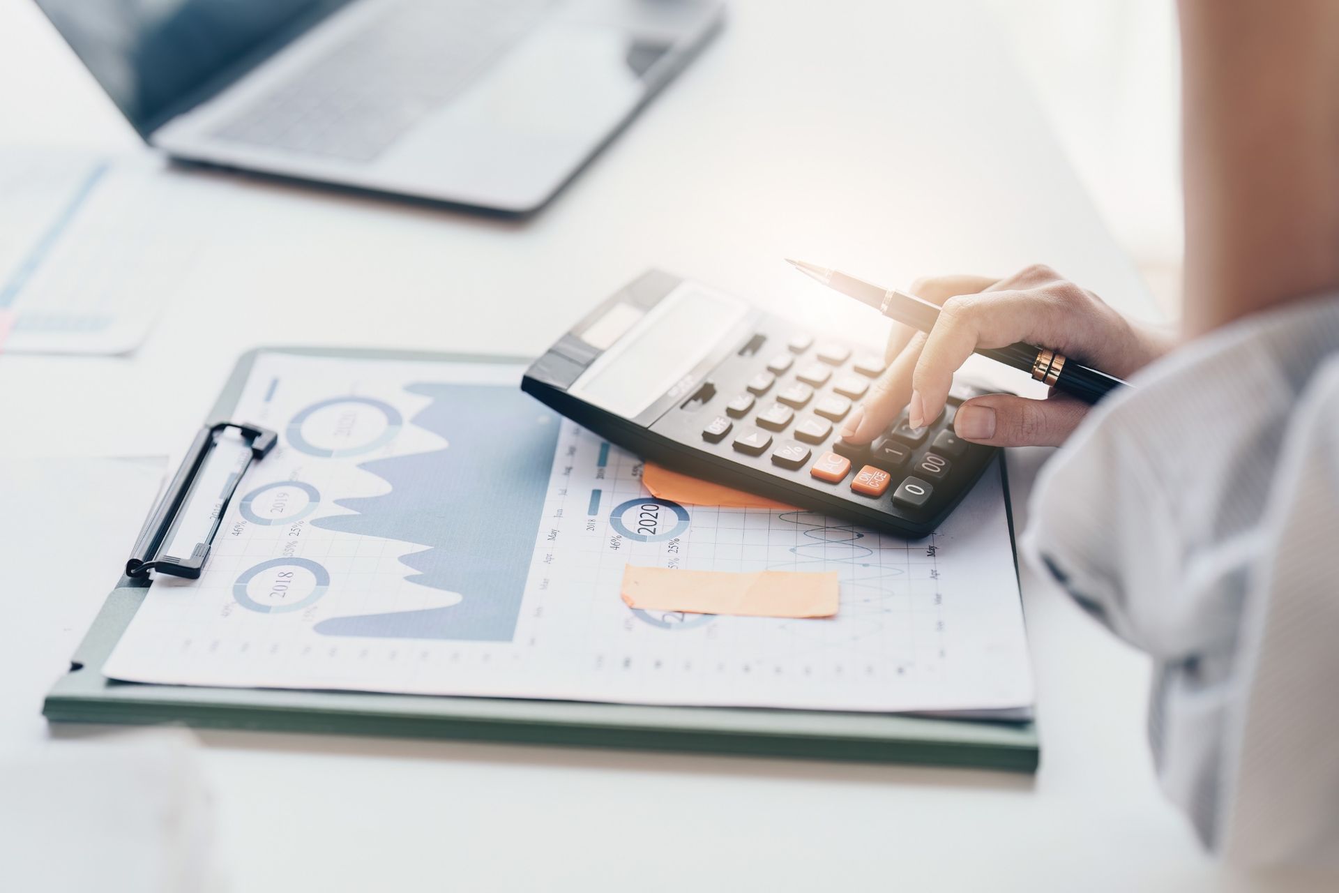 Una persona está usando una calculadora en un portapapeles.