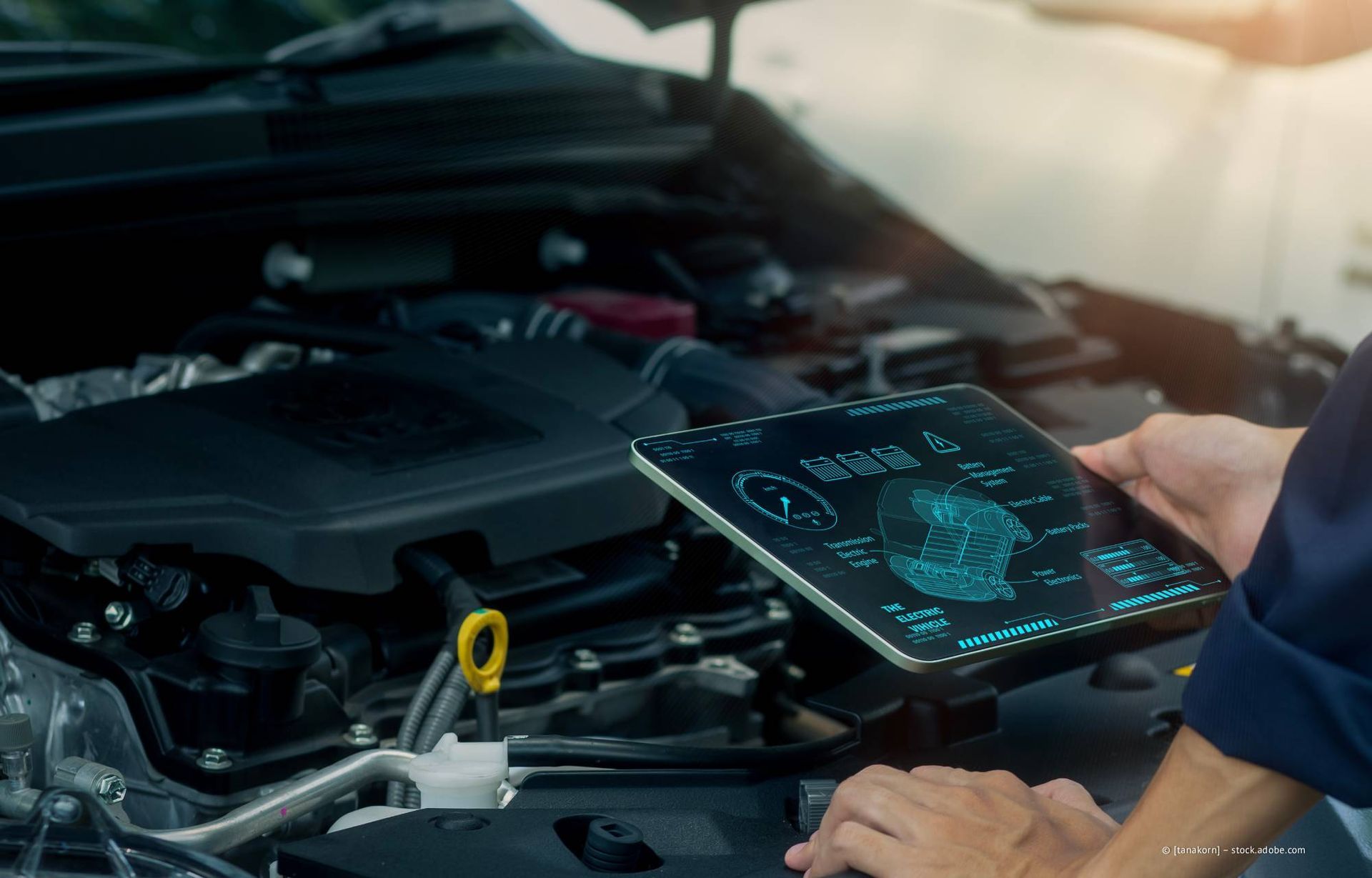 Ein Mechaniker benutzt ein Tablet zur Diagnose eines Automotors.