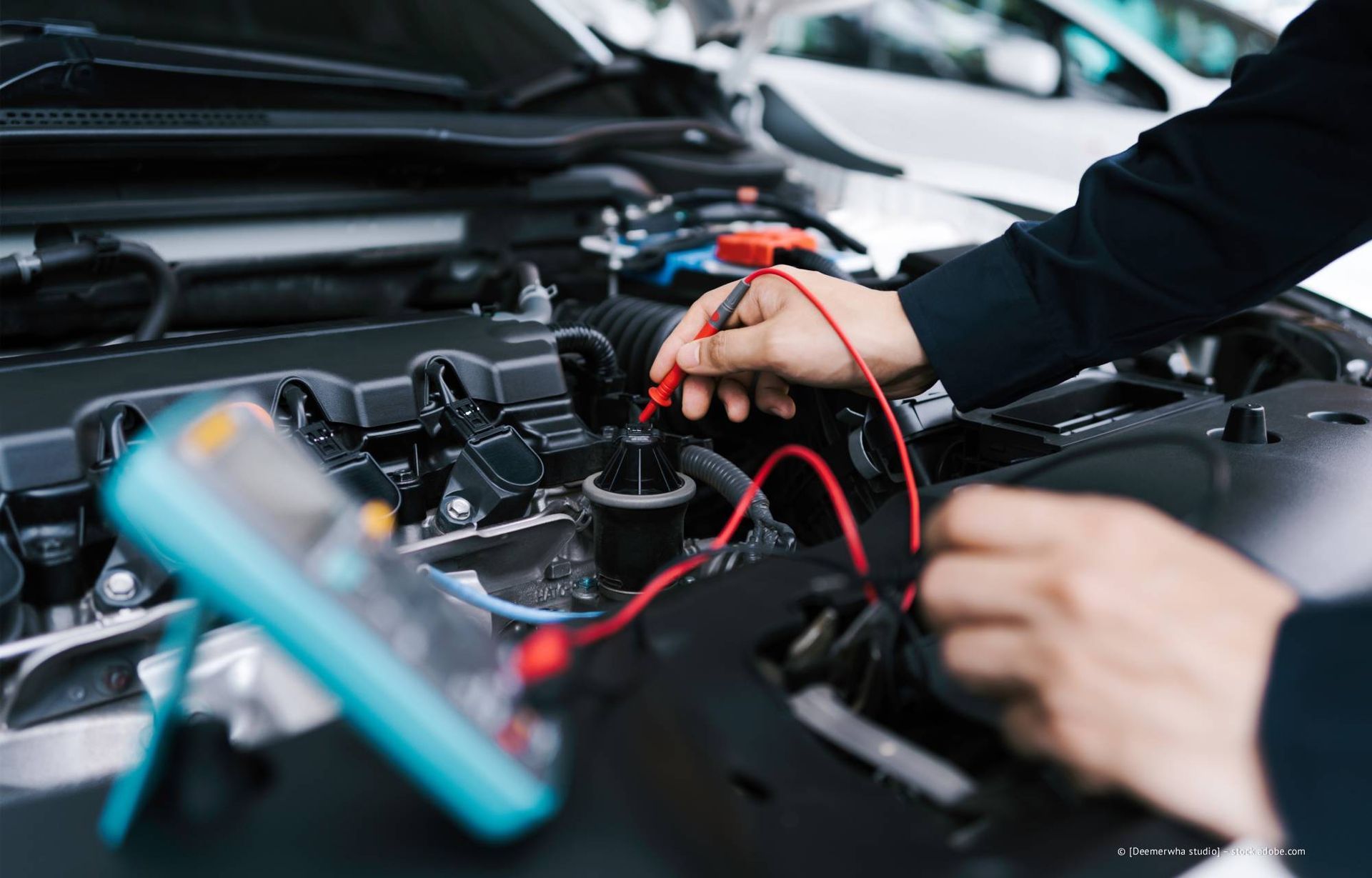 Eine Person, die mit einem Multimeter einen Automotor testet.