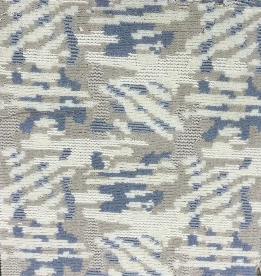 Tejido texturizado con un estampado de camuflaje pixelado repetitivo en tonos azules, blancos y gris claro.