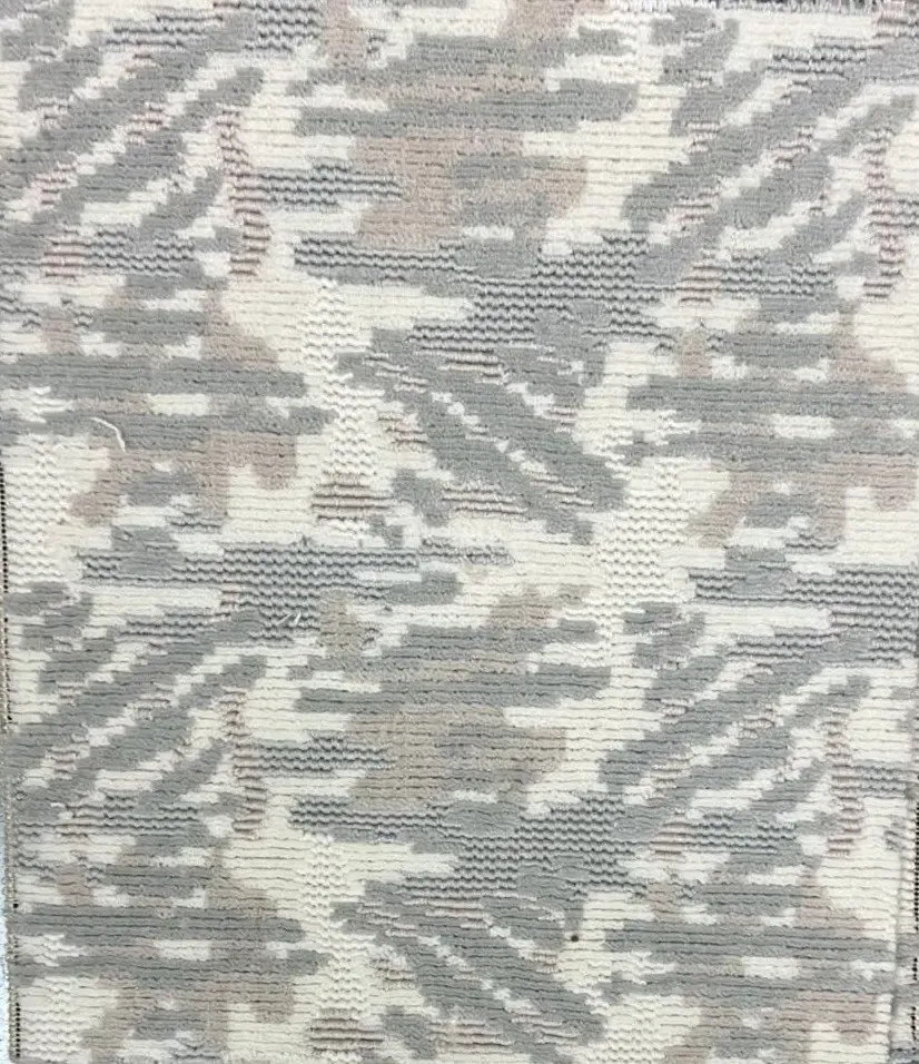 Primer plano de una tela con un estampado de camuflaje abstracto y texturizado en tonos crema, gris claro y beige apagado.