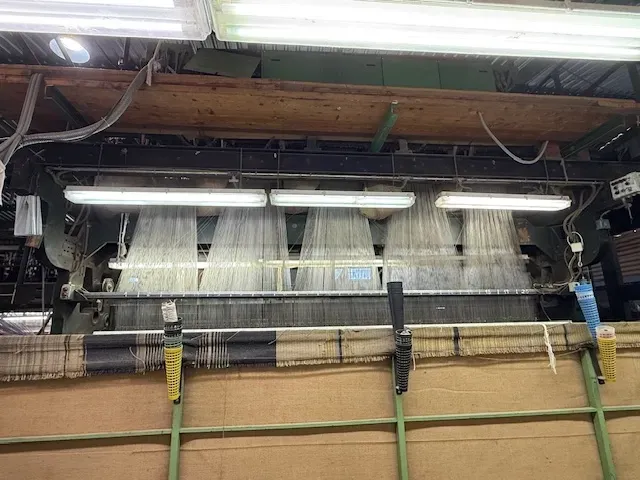 Vista de un telar textil con múltiples hilos blancos que se introducen en el mecanismo de tejido