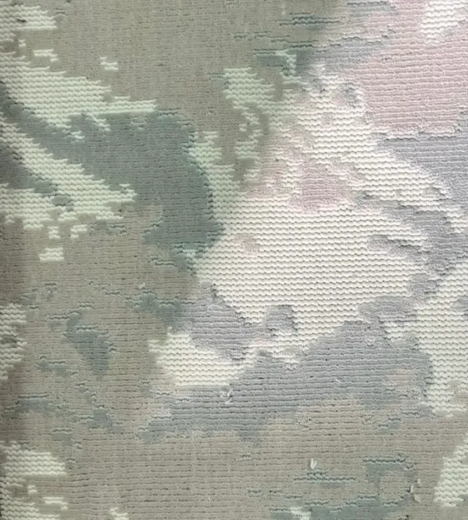 Vista de cerca de una tela texturizada con un estampado abstracto y suave en tonos apagados de verde, gris y rosa pálido.