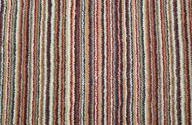 Un estampado de rayas verticales repetitivas en tonos marrones, rojos, crema, grises y negros