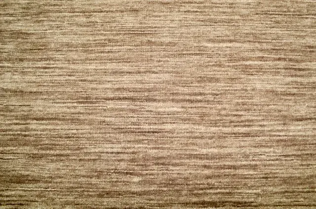 Un estampado de rayas verticales repetitivas en tonos marrones, rojos, crema, grises y negros
