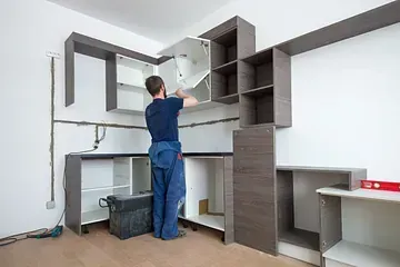 Un hombre está instalando gabinetes en una cocina.