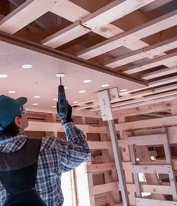 Un hombre está utilizando un taladro en un techo de madera.