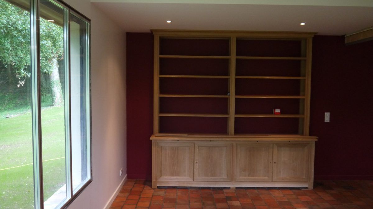 Une pièce avec un mur peint en rouge bordeaux avec une bibliothèque