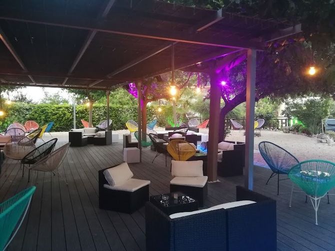 Un patio con muchas sillas y mesas bajo un dosel.