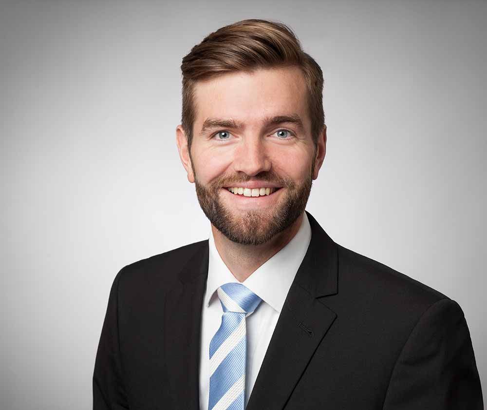 Ein Mann in Anzug und Krawatte lächelt in die Kamera. ein ideales Bewerbungsfoto